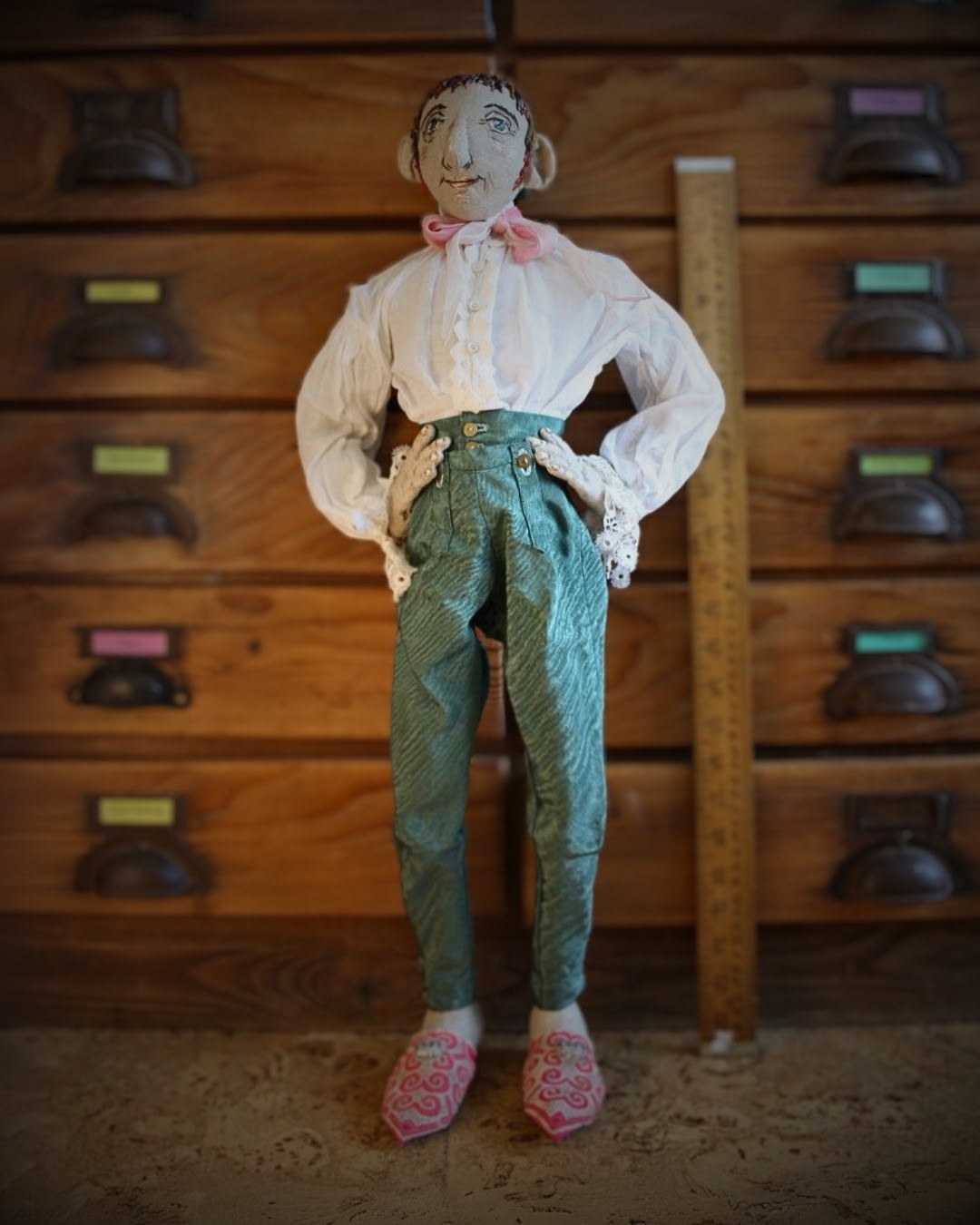 a doll standing in front of a wooden cabinet