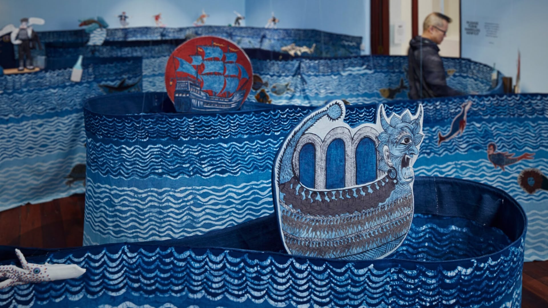 a blue fabric sea sculpture with a boat and a ship