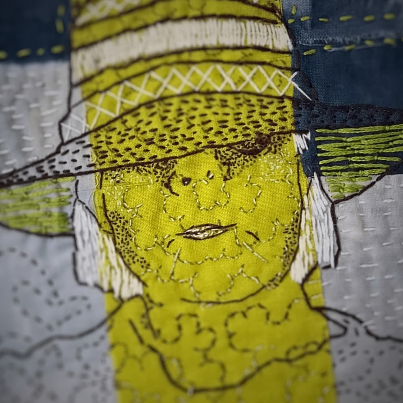 A close up of a stitched portrait depicting a woman wearing a large hat