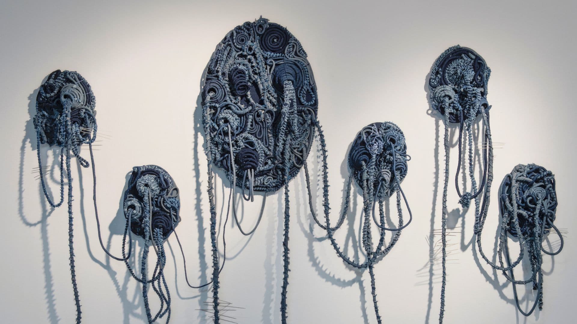 A collection of stitched sculptures on a white wall