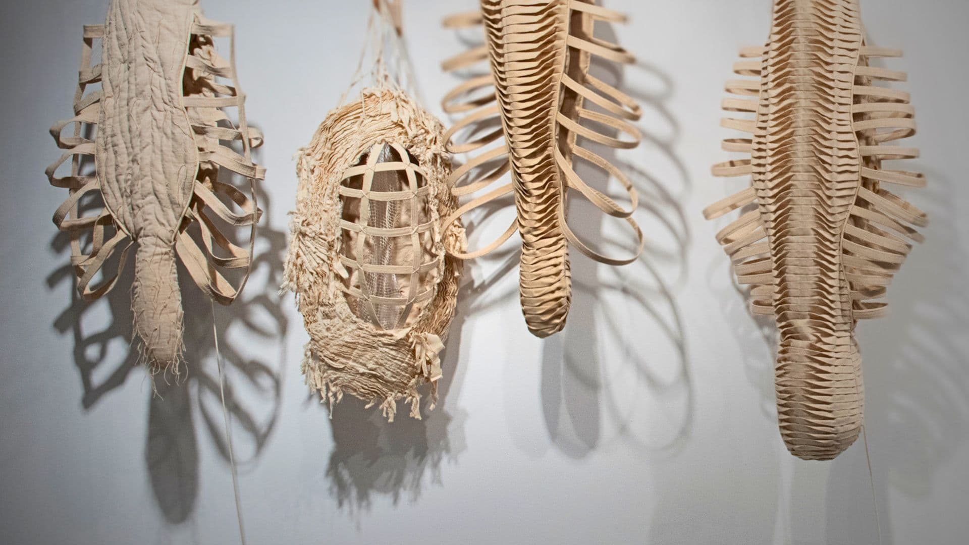 A group of stitched sculptures on a white wall