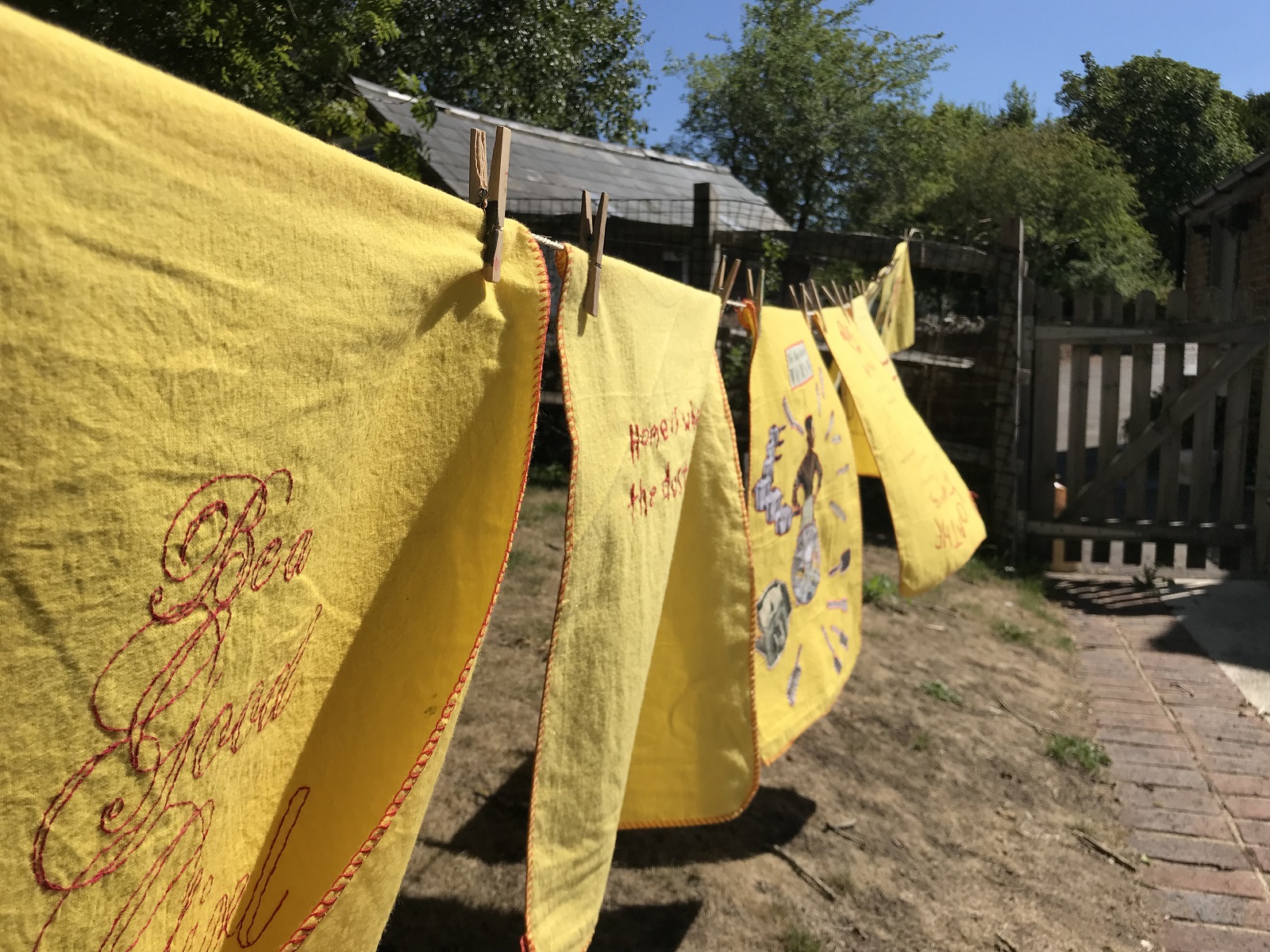 Vanessa Marr: A selection of duster submissions from the project on display in the garden of Ditchling Museum of Art and Craft (Detail), 2014-18, Each duster measures approx 35 x 50 cm, Embroidery on a duster