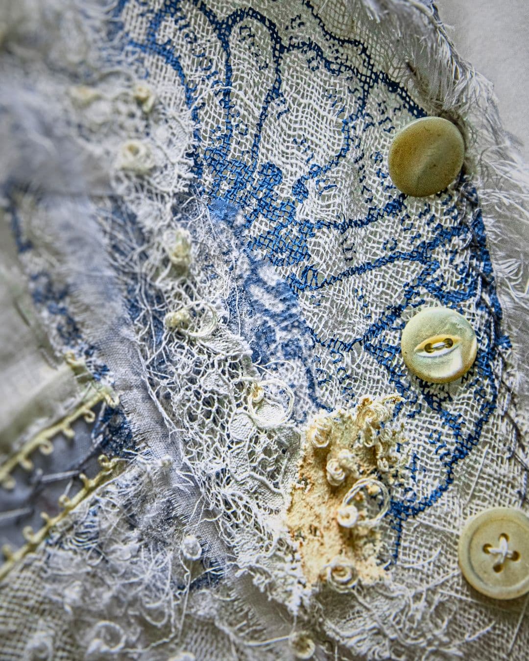 A close up of a fabric embelished with buttons and intricate stitches.