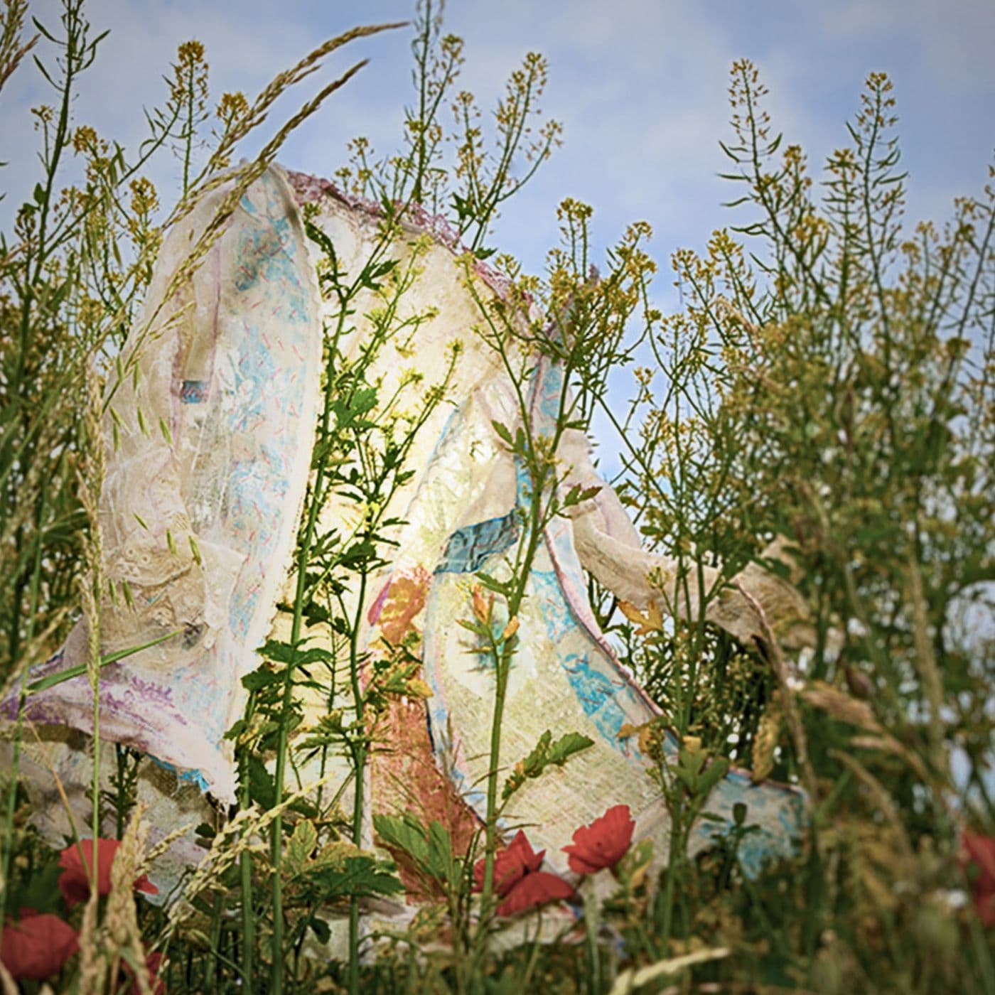 An art installation of a white shirt embellished with stitches in a meadow.