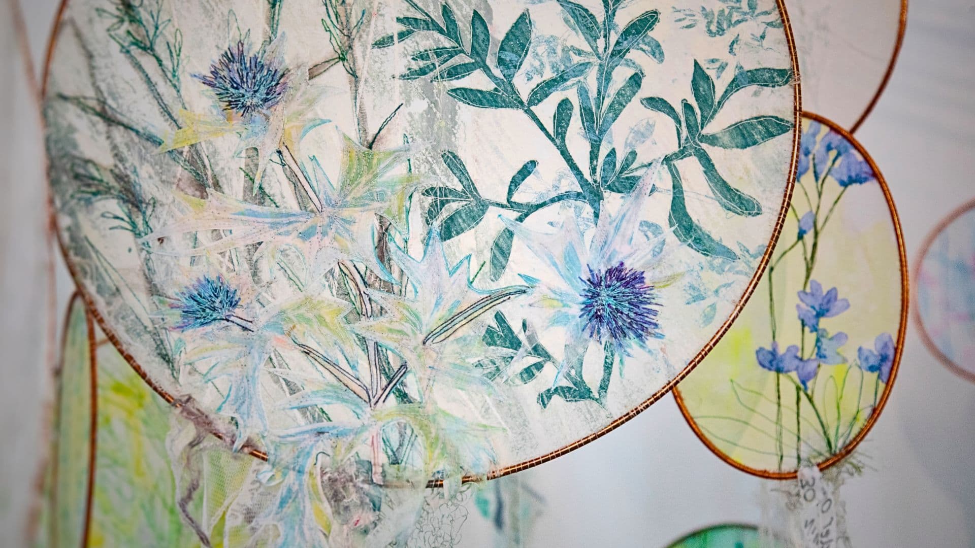 A close up of a stitched artwork of delicate blue flowers.