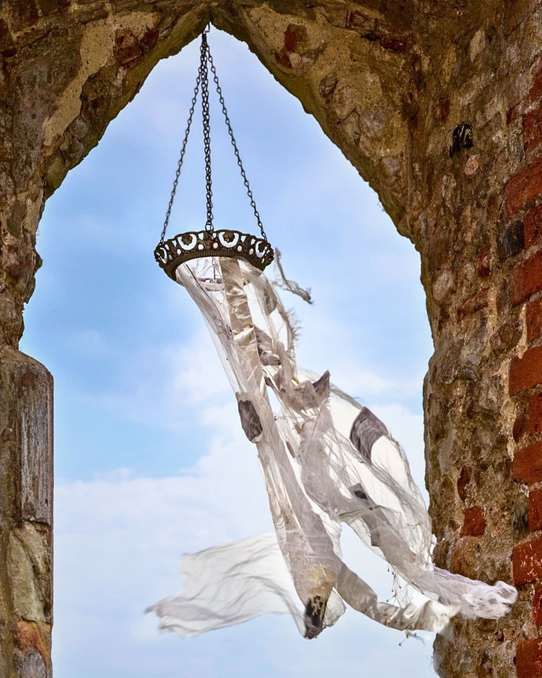 A basket with a white cloth dangling from a brick arch