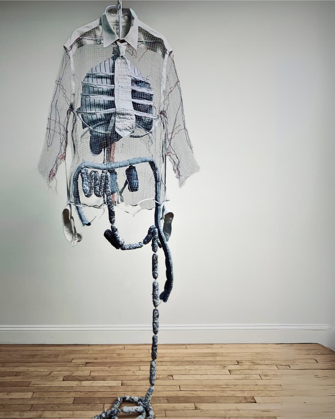 A sculpture of a shirt and ribs and internal organs of a man, hanging in a room.