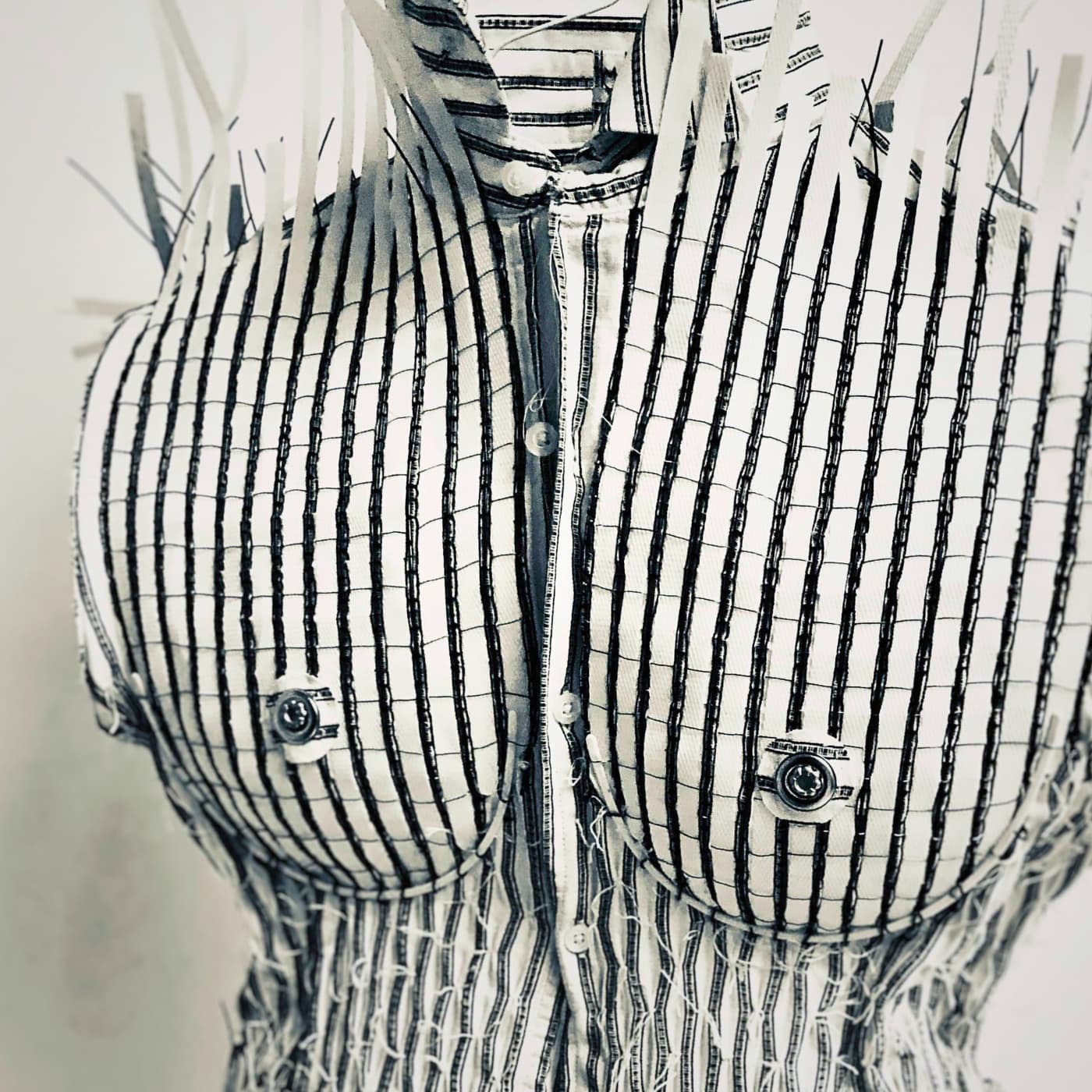 A black and white striped shirt made into a textile artwork of a woman's chest.