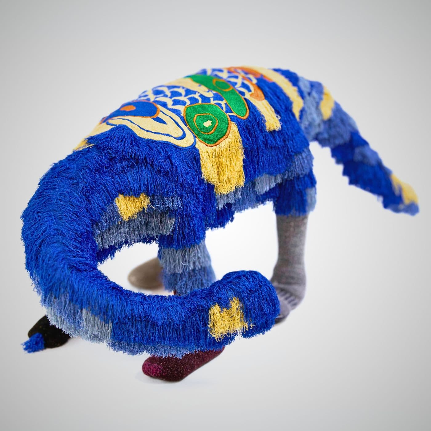 A stitched artwork of a Dinosaur embellished with colourful yarn.