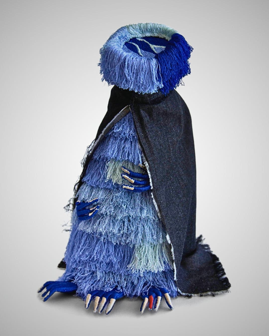 a blue and black stuffed animal wearing a cape. 