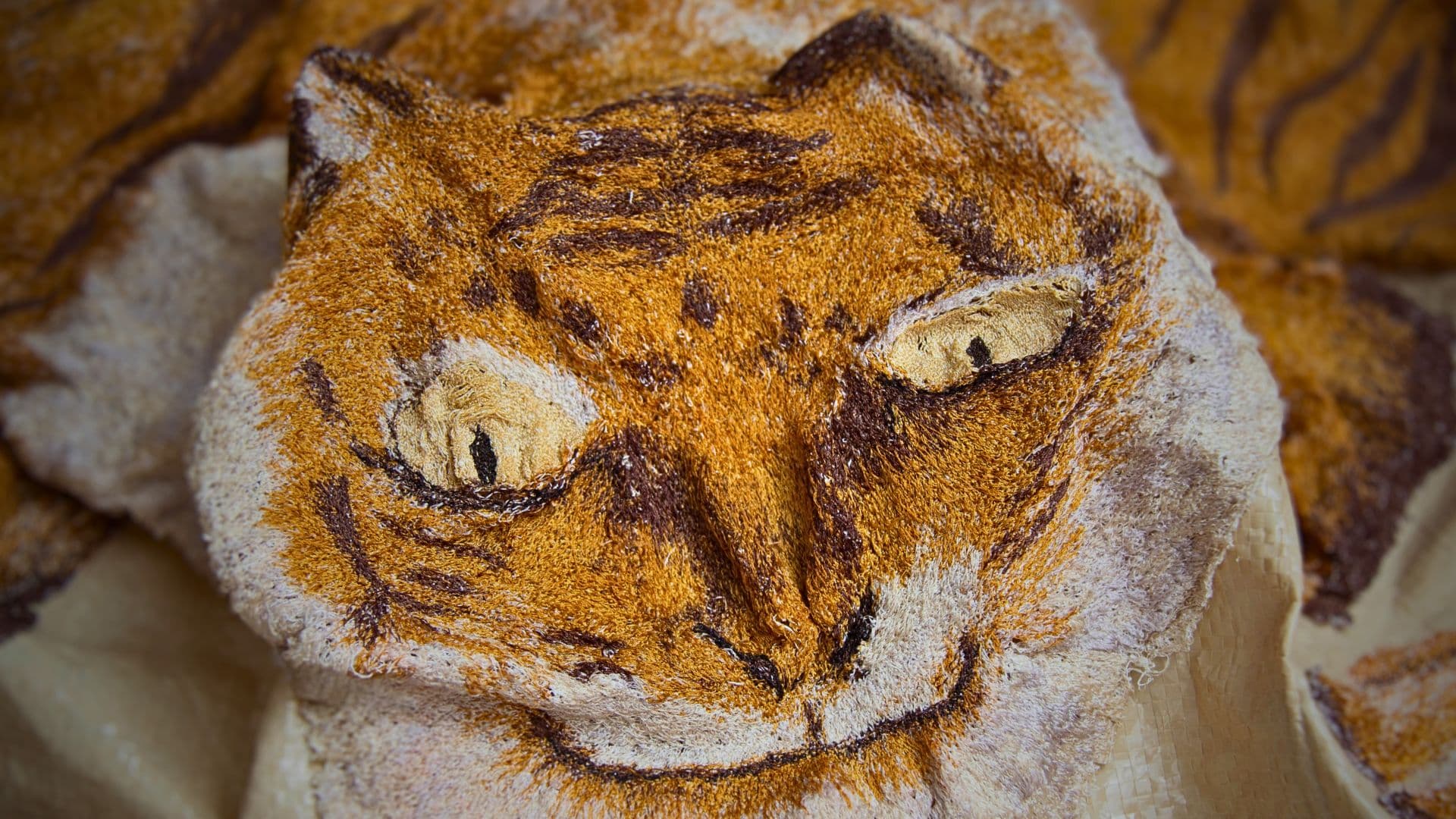 A close up of a stitched artwork of a Tiger's face.