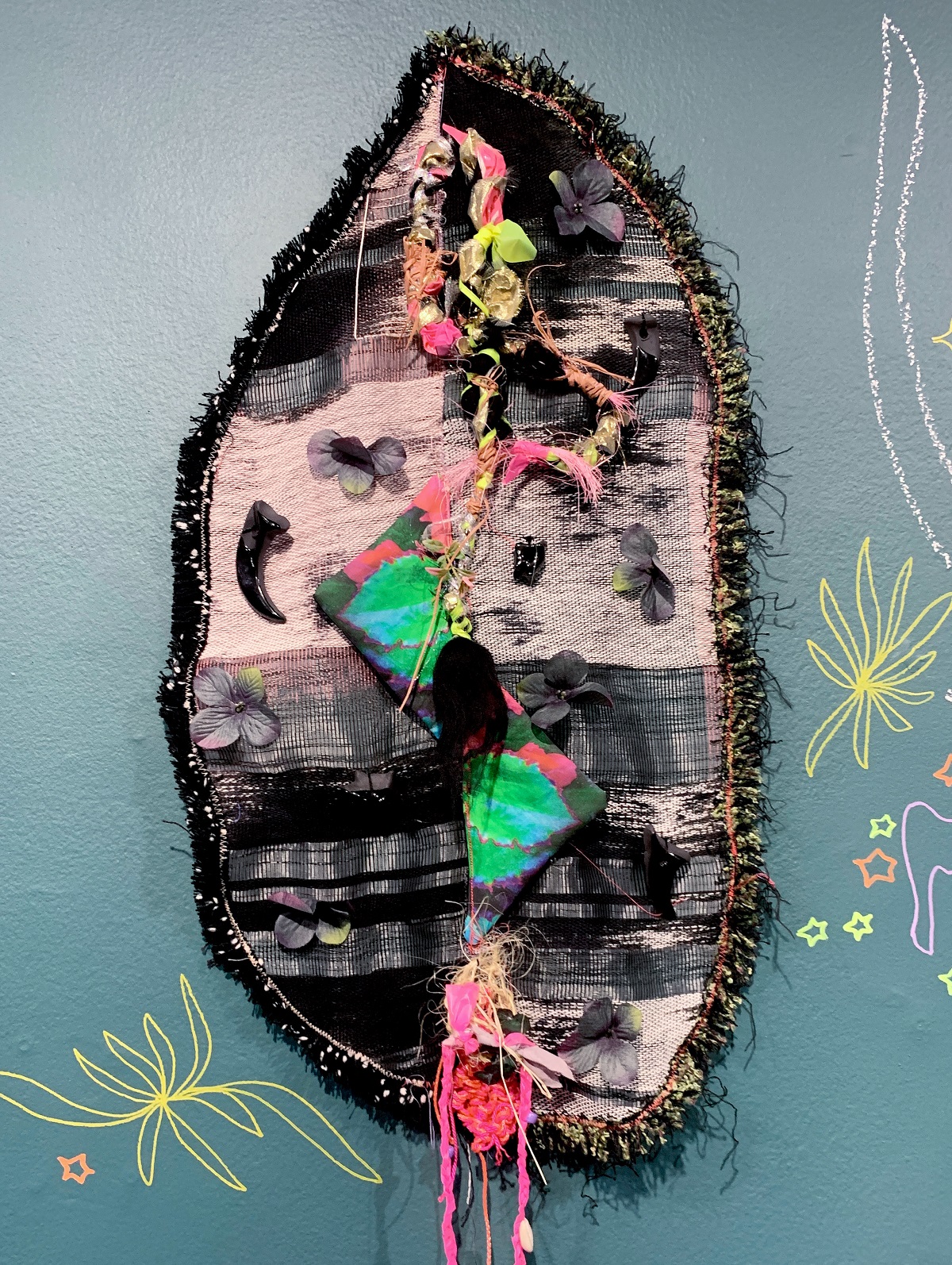 Zipporah Camille Thompson, chrysalis, 2021. 81cm x 38cm x 8cm (32" x 15” x 3"). Hand stitch, weaving. Handwoven hand-dyed fibre, digital photography printed on fabric, faux flowers, cotton, yarn, ribbon, raiffa, ceramic, cotton fringe. Photography: Mike Jensen.