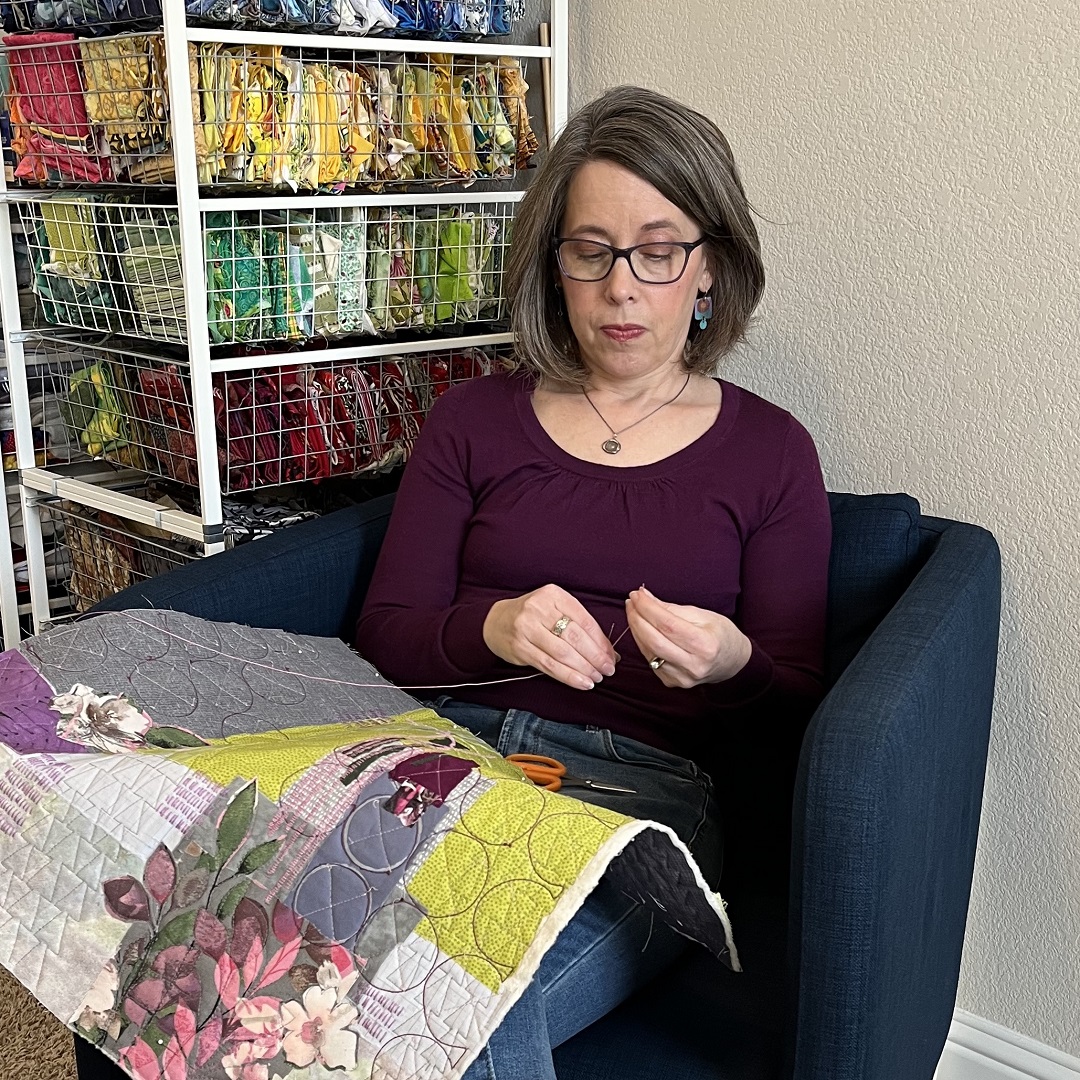 Deborah adding hand embroidered details to an art quilt collage in her studio.